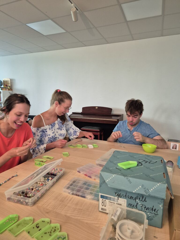 Klient*innen der Produktegruppe beim Perlen fädeln.